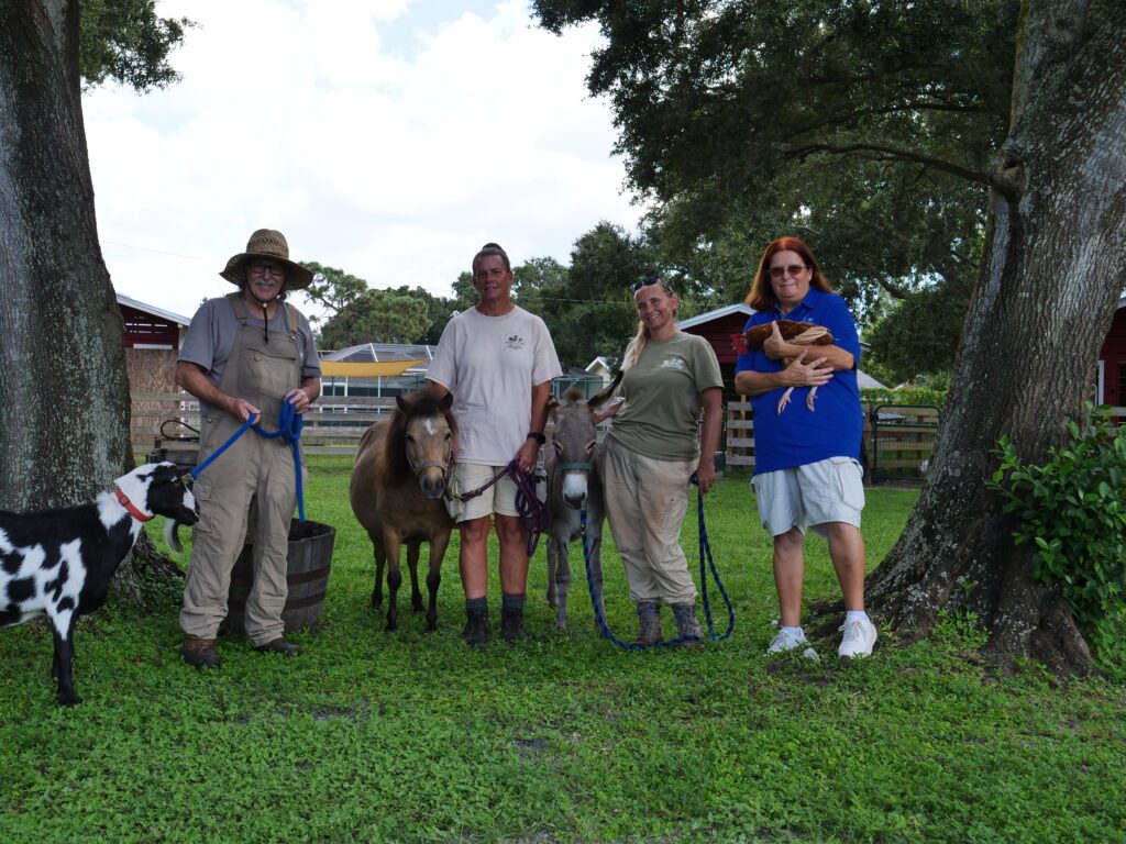 group of people pose with farm animals