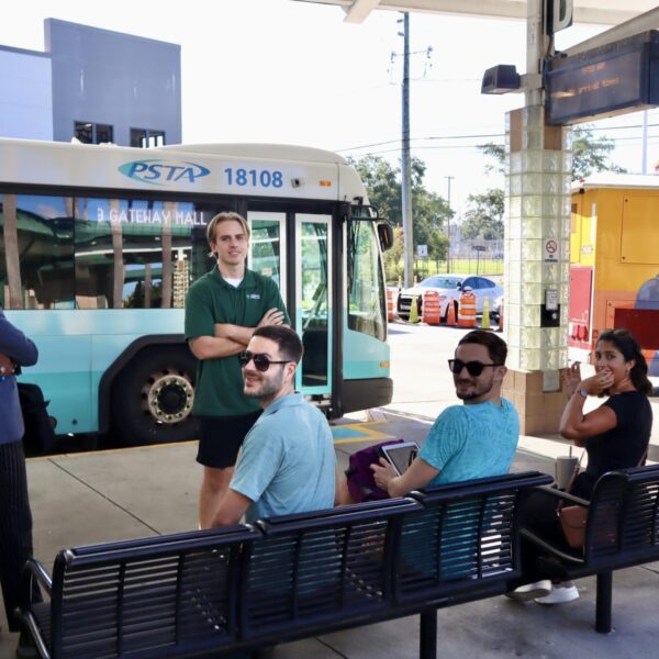 a group of people pose as they wait for the bus.