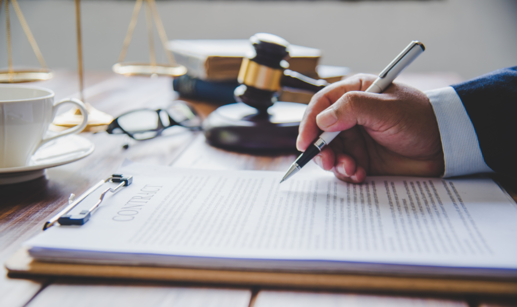 a business man's hand writing on a paper with a gavel in the background