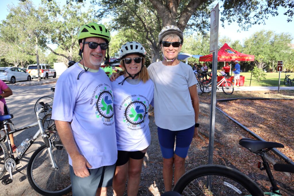 two women and one man standing with a bike