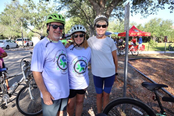 BYC participants two women and one man standing with a bike