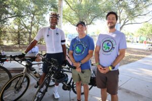 three men standing with a bike