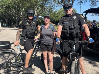 woman standing with two police officers on bikes