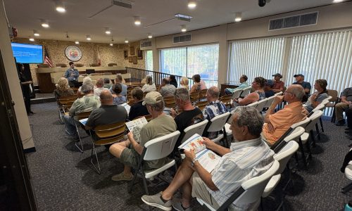 side view of a speaker addressing a room of people seated