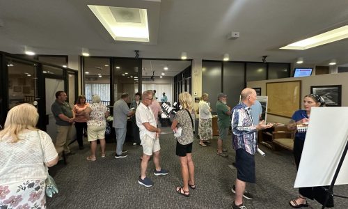 a group of people talking and standing amongst poster displays